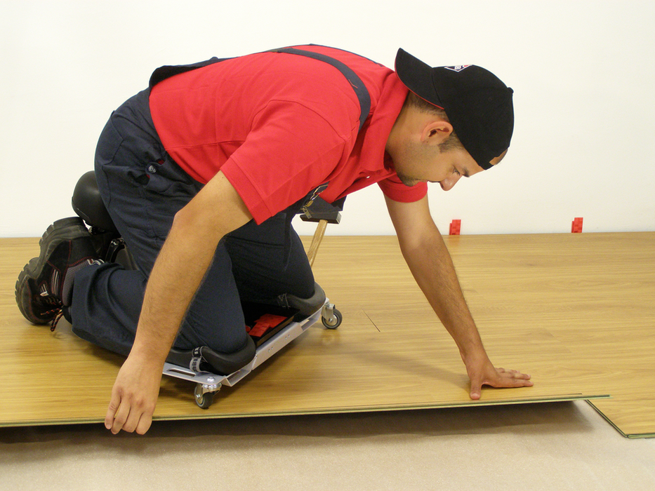 Operaio utilizza seduta ergonomica Rubi SR-1 durante installazione parquet