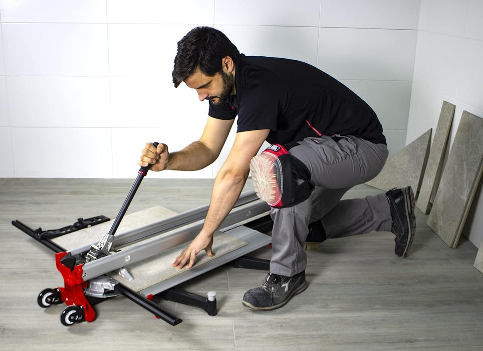 Operaio inginocchiato che taglia una lastra con tagliapiastrelle manuale Rubi TZ-1300 e indossa ginocchiere in gel per piastrellisti